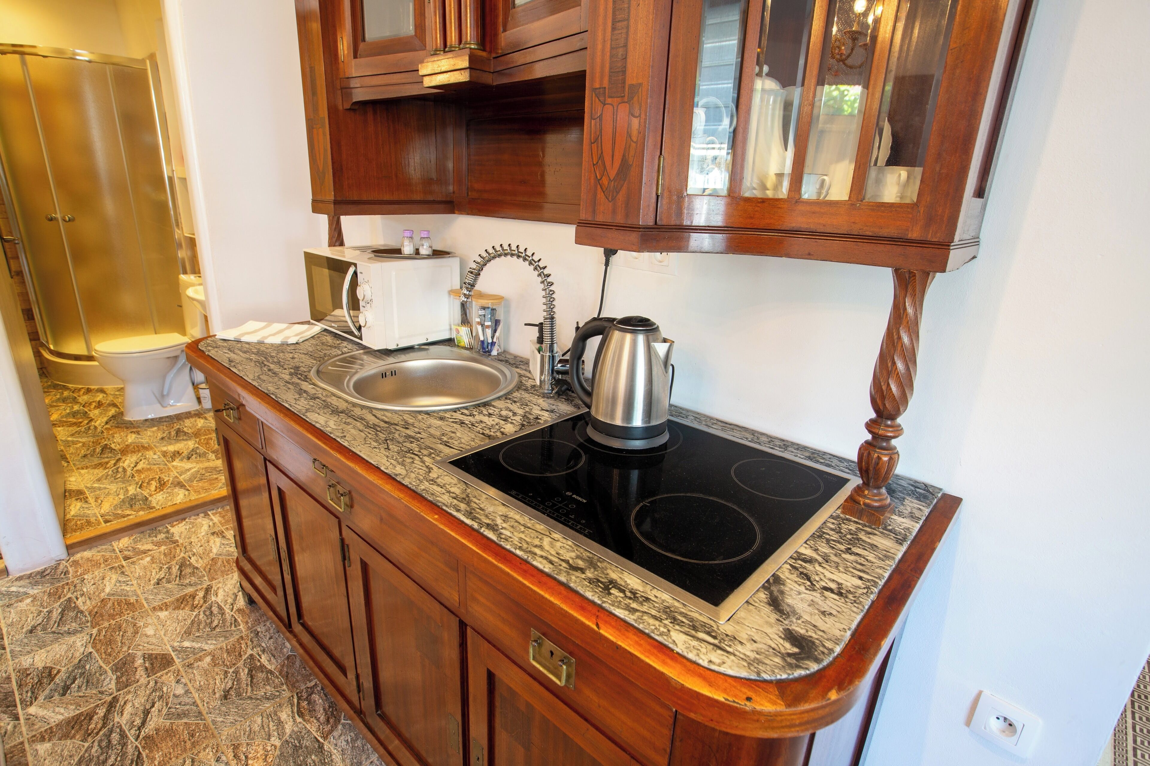 A kitchen with a granite countertop, stainless steel sink, and a black induction cooktop.