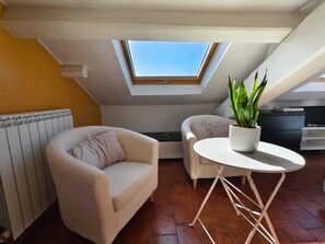 A cozy attic room with a skylight, two sofas, a small table, and a potted plant. - Cozy and bright loft studio in Milan (NO.LO) (Milano)