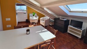 A compact living space with a dining table, a sofa, a TV, and a skylight. - Cozy and bright loft studio apartment in Milan (NO.LO) (Milano)