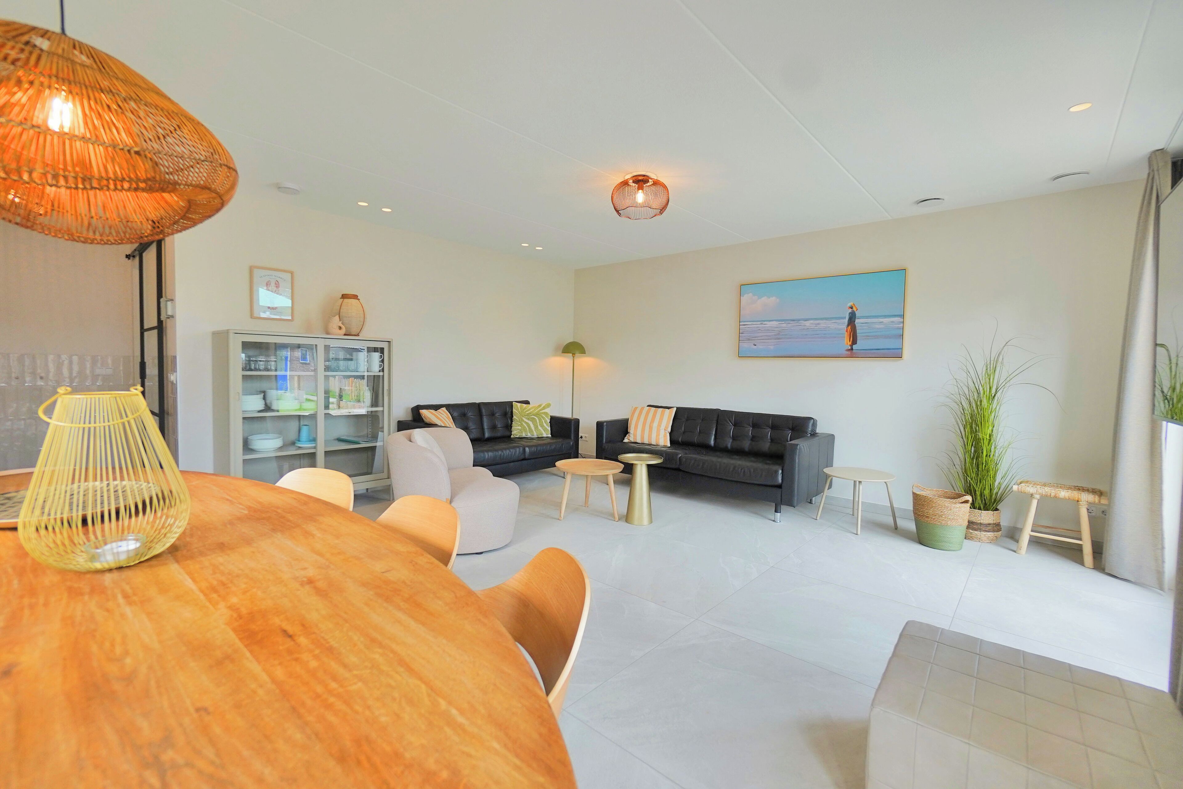 A modern living room with a wooden dining table, sofas, and a large painting on the wall.