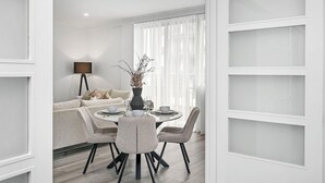 A modern dining area with a round table, chairs, and a vase of dried branches. - Modern City Escape | Stylish 2BR Apartment (East Perth)