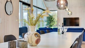 A modern dining area with a long table, decorative vases, and a blue sofa in the background.