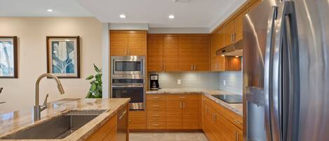 A modern kitchen with wooden cabinets, stainless steel appliances, and a granite countertop.