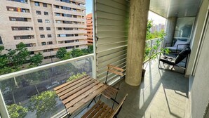 A balcony with a wooden bench, a concrete pillar, and a view of a cityscape. - Bielsa del Pilar - Turistea  (Zaragoza)