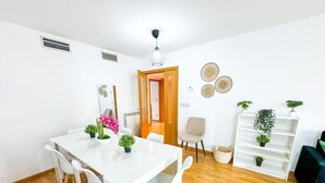 A modern dining area with a white table and chairs, a wooden floor, and a bookshelf with plants. - Bielsa del Pilar - Turistea  (Zaragoza)
