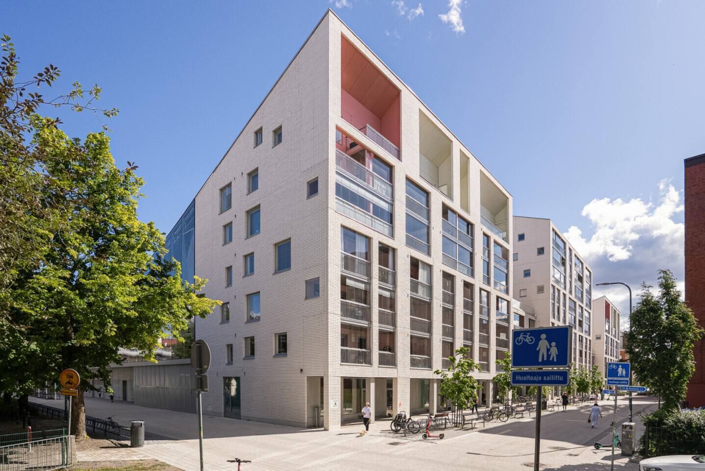 A modern building with multiple floors, large windows, and a balcony area.