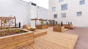 Eine Holzterrasse im Freien mit Pflanzkübeln und Sitzbereichen.