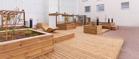 An outdoor wooden deck with planters and seating areas.