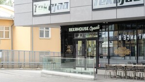 Een gebouw met een glazen etalage waarop 'BEERHOUSE Opali' staat en een bord met 'LIVE SPORTS'.