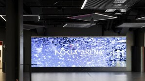 Een modern interieur met een groot scherm waarop 'NOKIA ARENA' staat, een metalen kolom en een strak betegelde vloer.