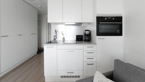 Een moderne keuken met witte kastjes, een inbouwoven en een koffiezetapparaat.