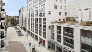 A multi-story building with a modern design, featuring balconies, large windows, and a flat roof with outdoor seating. - Modern studio with own glazed balcony for 3 people (Tampere)