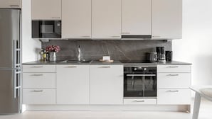 A modern kitchen with a built-in oven, a microwave, and a coffee maker. - Modern studio with own glazed balcony for 3 people (Tampere)