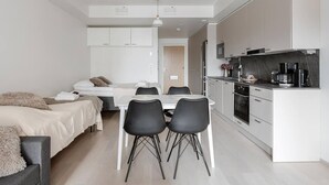 A modern, compact hotel room with a kitchenette, a dining area with a table and chairs, and a separate sleeping area with a bed. - Modern studio with own glazed balcony for 3 people (Tampere)