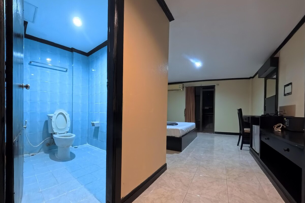 A modern bathroom with a toilet and shower, a bedroom with a bed and nightstand, and a living area with a sofa and TV.