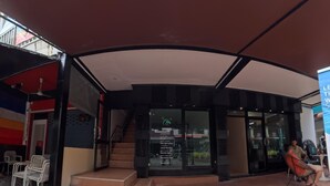 A hotel entrance with a covered outdoor area, a staircase leading to the entrance, and a seating area with a person sitting on a chair. - Stay 94 Patong (Patong)
