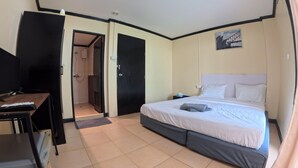 A hotel room with a bed, a desk, a TV, and a shower area. - Stay 94 Patong (Patong)