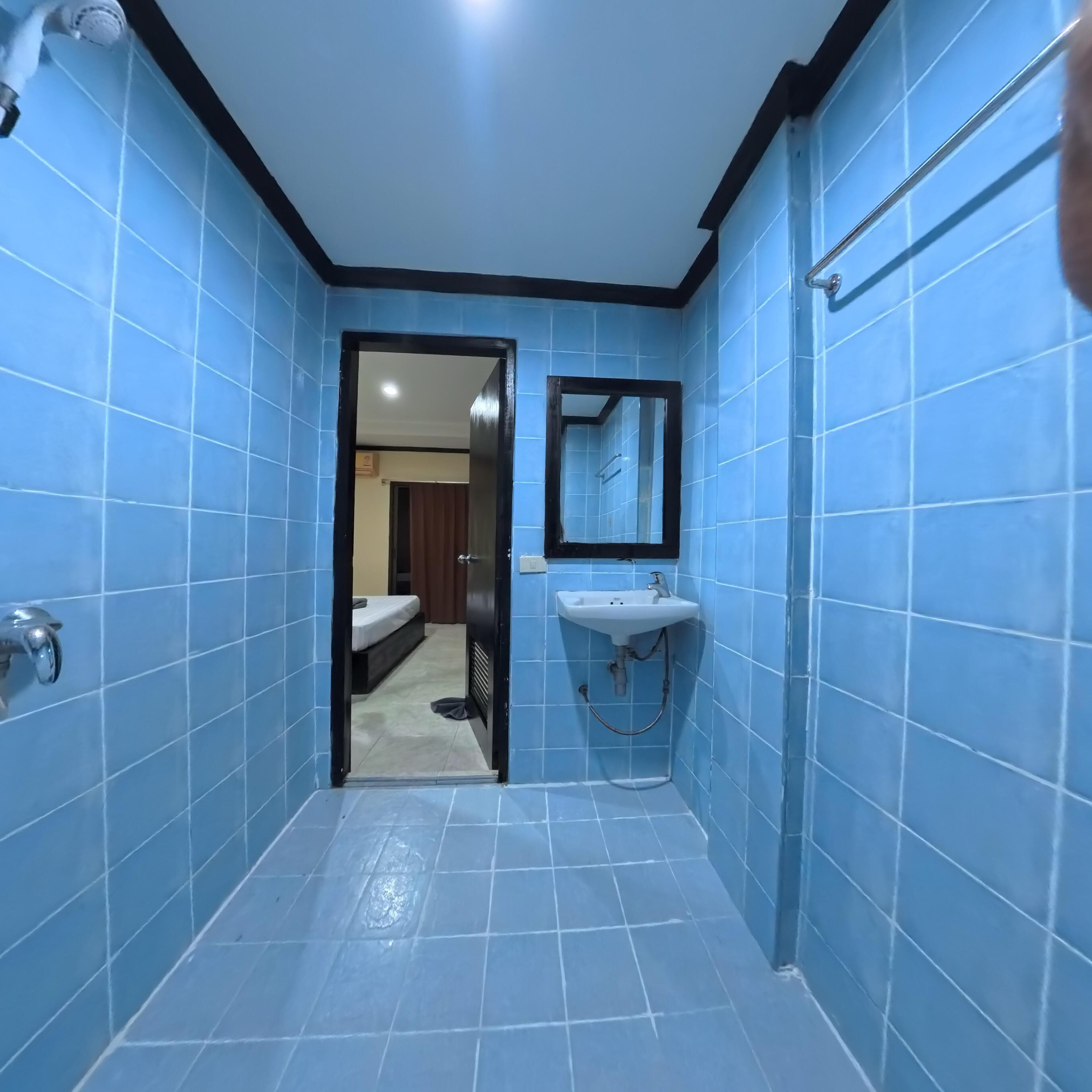 Une salle de bain avec des carreaux bleus, un lavabo, un miroir et une douche.