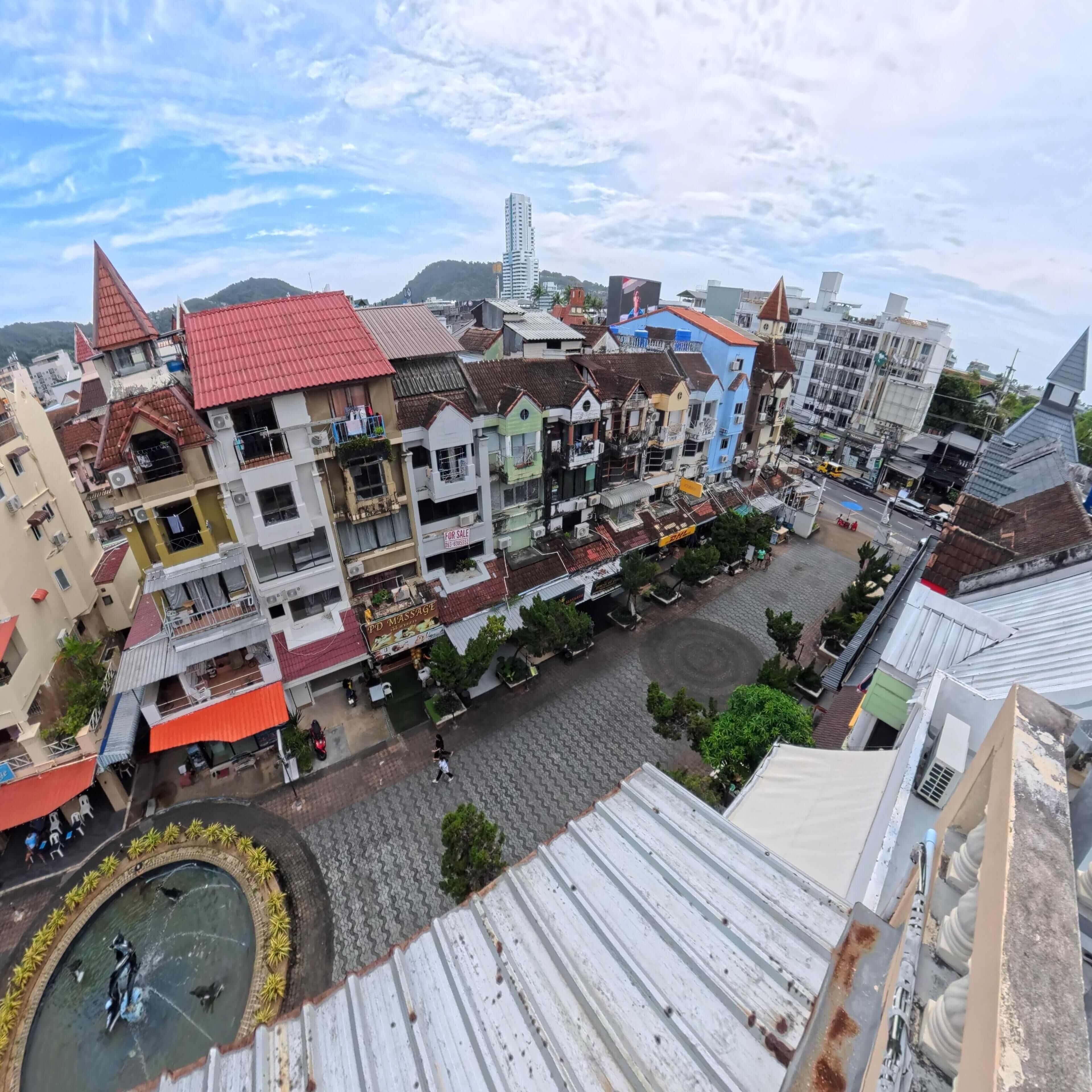 A cityscape with a variety of buildings, including a massage parlor and a shop with a 'For Sale' sign.