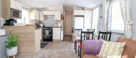 A compact living space with a kitchenette, a dining area, and a seating area with a sofa and chairs.