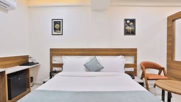 Ein Hotelzimmer mit einem Bett, einem Schreibtisch, einem Sessel und zwei gerahmten Bildern an der Wand.