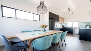 A modern kitchen with dark cabinets, a stainless steel refrigerator, and a window overlooking the dining area. - Helios Heights - Modern 2 storey, Off Peak Special available (Moonta Bay)