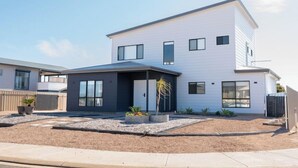 A modern two-story house with a flat roof, large windows, and a well-maintained front yard with gravel and plants. - Helios Heights - Modern 2 storey, Off Peak Special available (Moonta Bay)