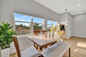 A dining area with a wooden table and chairs, large windows, and a view of the outside. - 10 Guests Welcome! Luxury Townhome & Arcade Games (Tampa)