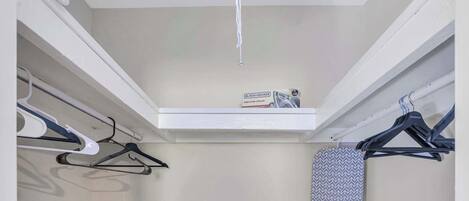 A closet with hanging space, a shoe rack, and a ceiling-mounted light fixture.
