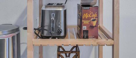 A kitchenette with a toaster, a coffee maker, and a box of McCafé coffee.