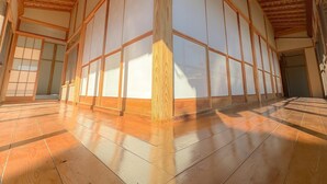Une pièce de style japonais traditionnel, avec un sol recouvert de tatamis, des portes coulissantes et des poutres en bois.
