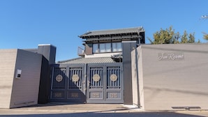Une porte japonaise traditionnelle, ornée de motifs dorés, qui mène à un bâtiment à la façade moderne, sur lequel on peut lire l’inscription « Jun Resort ».