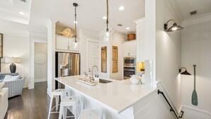 A modern kitchen with a large island, white cabinetry, stainless steel appliances, and pendant lighting. - ☀️ Sun & Sand for 6! NEW 6 Seater Golf Cart | Heated Pool | 4 Bikes 🚲 (Santa Rosa Beach)
