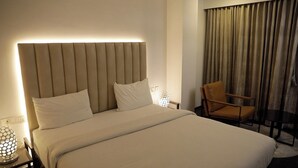 A hotel room with a large bed, a chair, and a lamp. - Vanaalayam Retreat Palladam by Arcadia (Palladam)