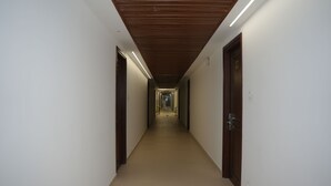 A corridor with wooden doors and a lighted ceiling. - Vanaalayam Retreat Palladam by Arcadia (Palladam)