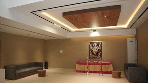 A modern interior with a wooden ceiling, a sofa, a small table, and a decorative altar. - Vanaalayam Retreat Palladam by Arcadia (Palladam)