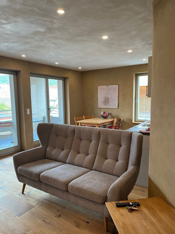 A modern living room with a sofa, a dining table, and a map on the wall.