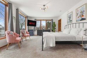 Un dormitorio moderno con una cama, un televisor, un escritorio y una silla.