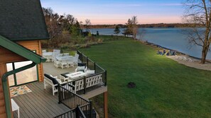 Una terraza con mobiliario exterior, un brasero y vistas a un lago.