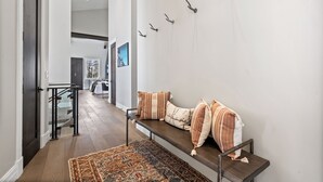 A modern interior with a bench, a patterned rug, and wall-mounted hooks.