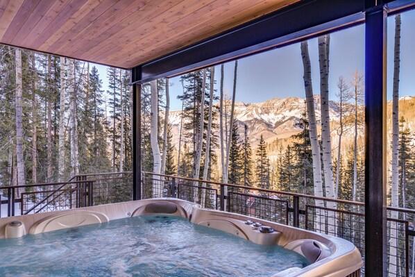 A hot tub with a mountain view, surrounded by tall trees and a wooden ceiling. - Modern Luxury - Mountain Village Chalet - Ski-In/Walk-Out - Sauna - Hot Tub (Mountain Village)
