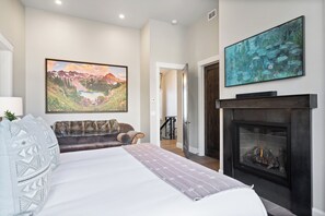Un dormitorio con una cama grande, una chimenea y dos cuadros en las paredes.