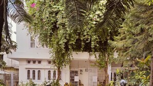 A courtyard with a white building, potted plants, and parked motorcycles. - LOKTAK RESIDENCY (Guwahati)