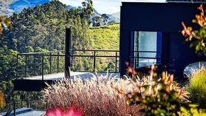 A modern building with large windows overlooking a lush landscape. - Loft in the Mantiqueira house. (Gonçalves)