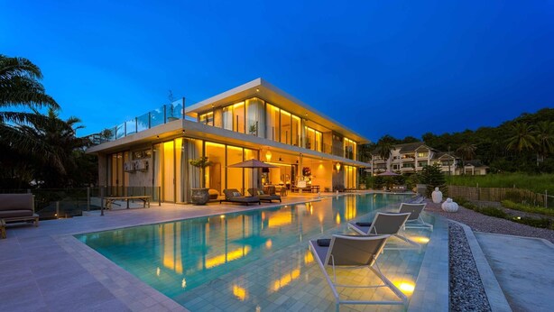 A modern two-story house with a swimming pool, outdoor seating, and a well-lit patio area. - Ultra-Modern 6-Bedroom in GolfCourse PH6 (Cha-am)