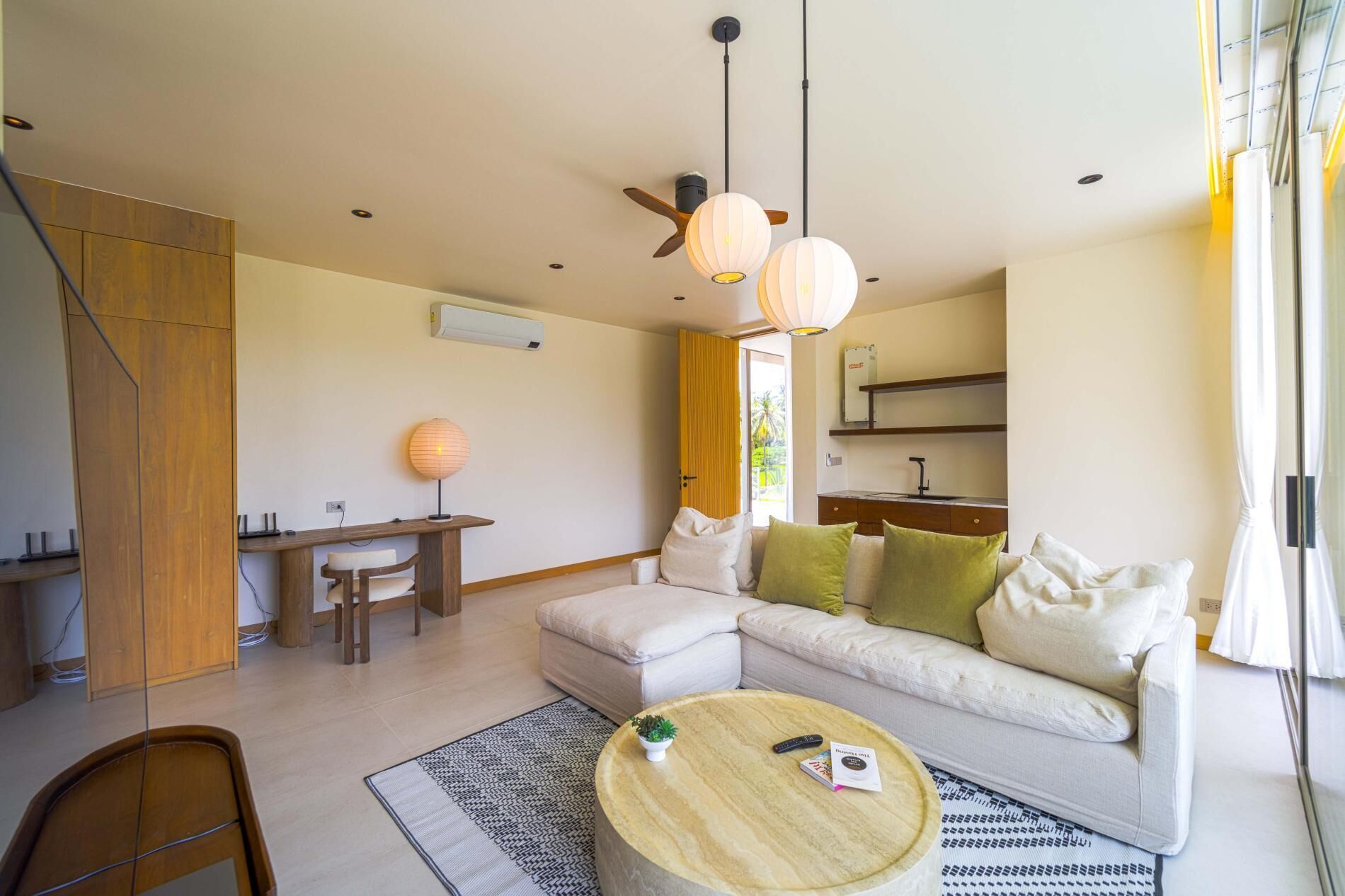 A modern living room with a sofa, a round coffee table, a dining area with a table and chairs, and a ceiling fan.
