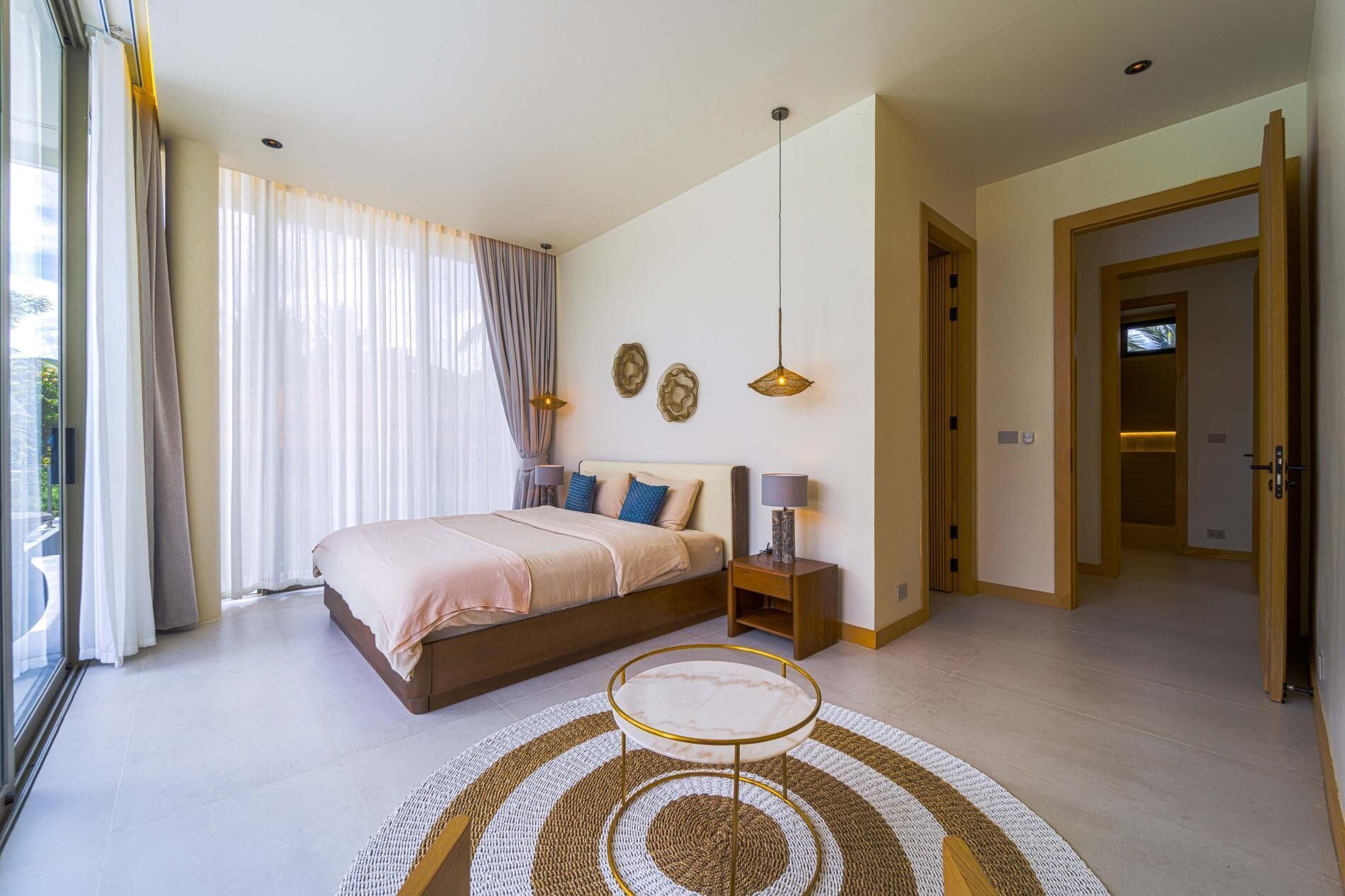 A bedroom with a bed, bedside table, lamp, and a round coffee table.