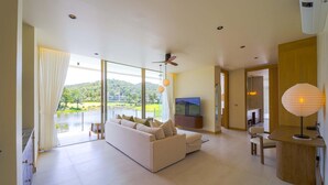 A spacious living area with a large sofa, a TV, and a dining table. - Ultra-Modern 6-Bedroom in GolfCourse PH6 (Cha-am)