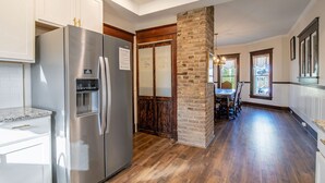 Una cocina moderna con electrodomésticos de acero inoxidable, piso de madera y una pared de ladrillo decorativa.