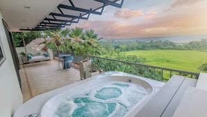 A hot tub on a balcony with a view of a green field and the ocean. - Villa Marala (Parrita)